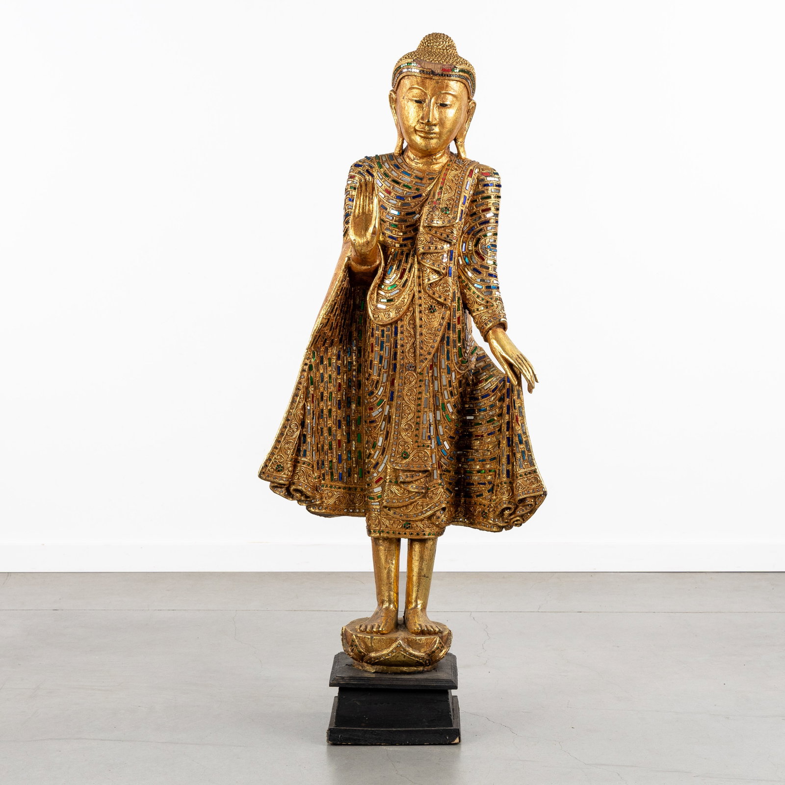 A Decorative statue of a Standing Burmese Buddha, Abhaya mudra, sculptured and gilded wood.: A Decorative statue of a Standing Burmese Buddha, Abhaya mudra, sculptured and gilded wood. Sculptured, patinated, and gilded wood.Burmese standing Buddha, in Abhaya mudra posture.Richly finished wi