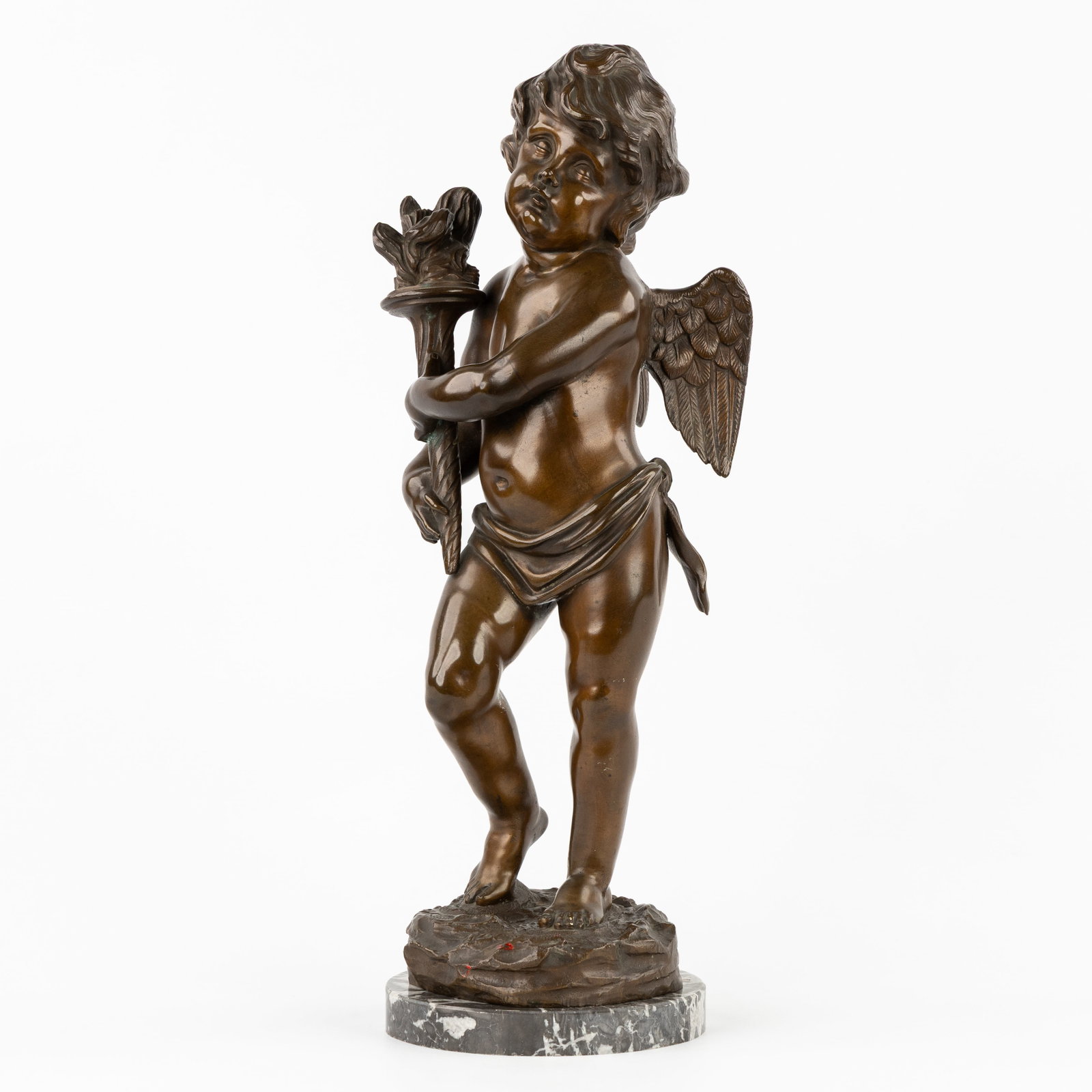 A Putto or Cherub with a torch, patinated bronze, in the style of Moreau.: A Putto or Cherub with a torch, patinated bronze, in the style of Moreau. Patinated bronze.Unsigned, in the style of Moreau.Standing on a marble base (H: 2 cm x D: 15 cm). (17 x 43.5 x 16 c
