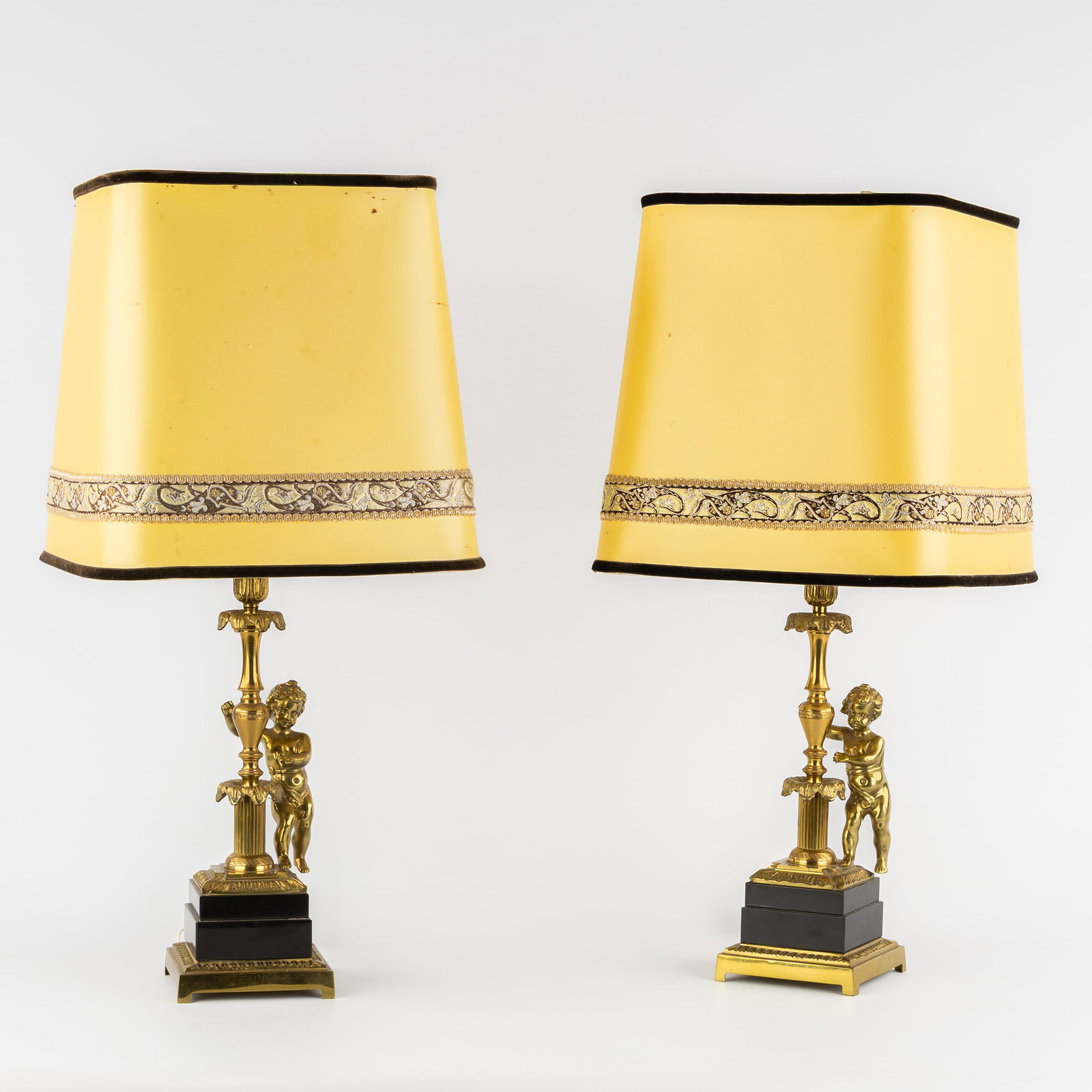A Pair of table lamps with Putti, brass and marble, Hollywood Regency style, circa 1970.: A Pair of table lamps with Putti, brass and marble, Hollywood Regency style, circa 1970. Brass/bronze and black marble.Decorated with putto, acanthus leaves, and palmette moldings.Hollywood Regency