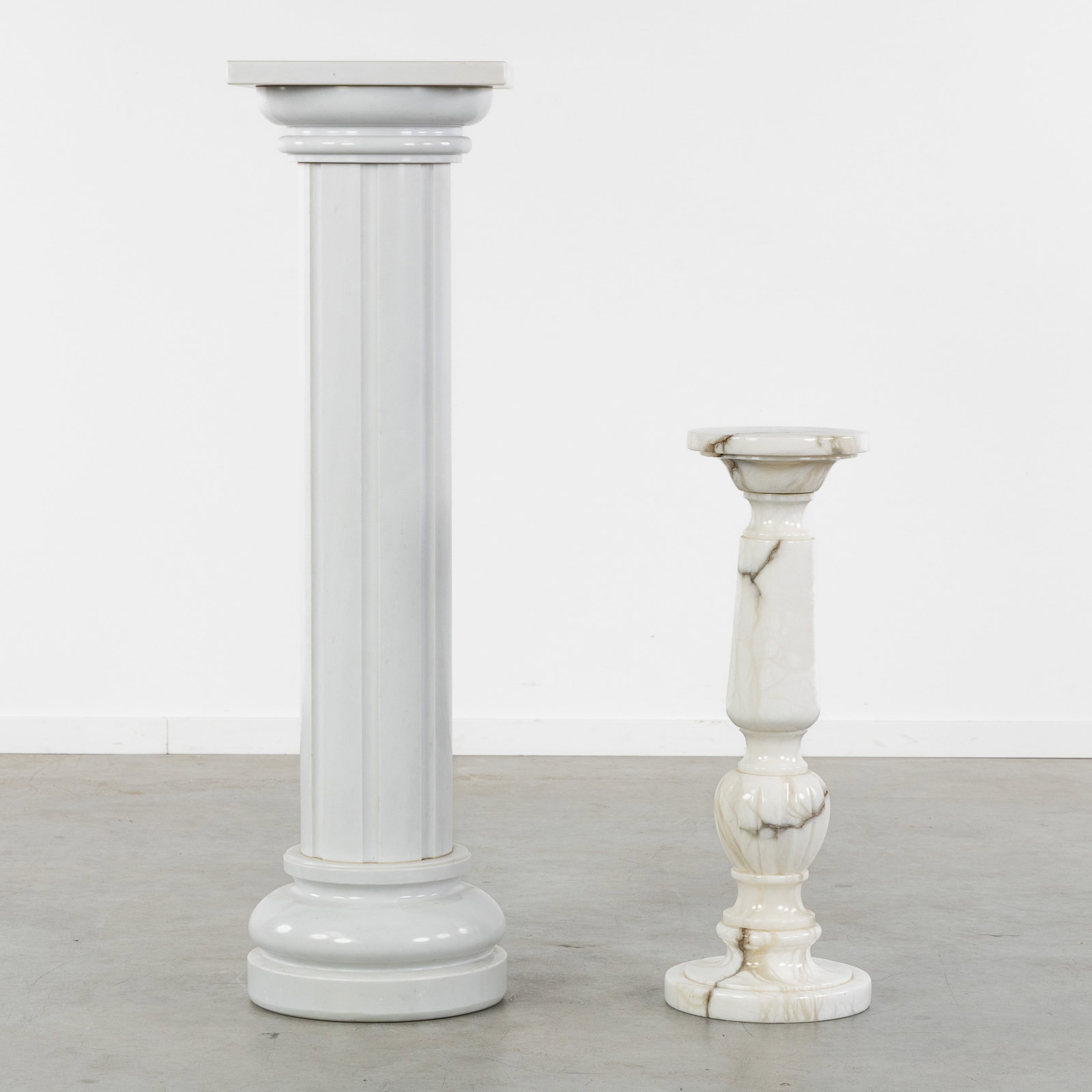 Two marble consoles or pedestals, baluster shaped and column, 20th C.: Two marble consoles or pedestals, baluster-shaped and columnar, 20th century. Sculptured white marble.Baluster-shaped console (H: 75 cm - diameter platform: 24 cm).Columnar console (H: 122 cm - plat