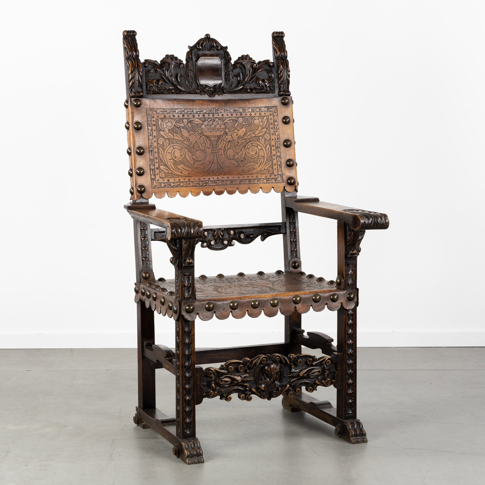 A Spanish Throne chair, Sculptured wood and Cordoba leather, Renaissance style, circa 1900.: A Spanish Throne chair, Sculptured wood and Cordoba leather, Renaissance style, circa 1900. Sculptured wood and Cordoba leather.Throne chair, with leather seat and backrest, finished with decorative n