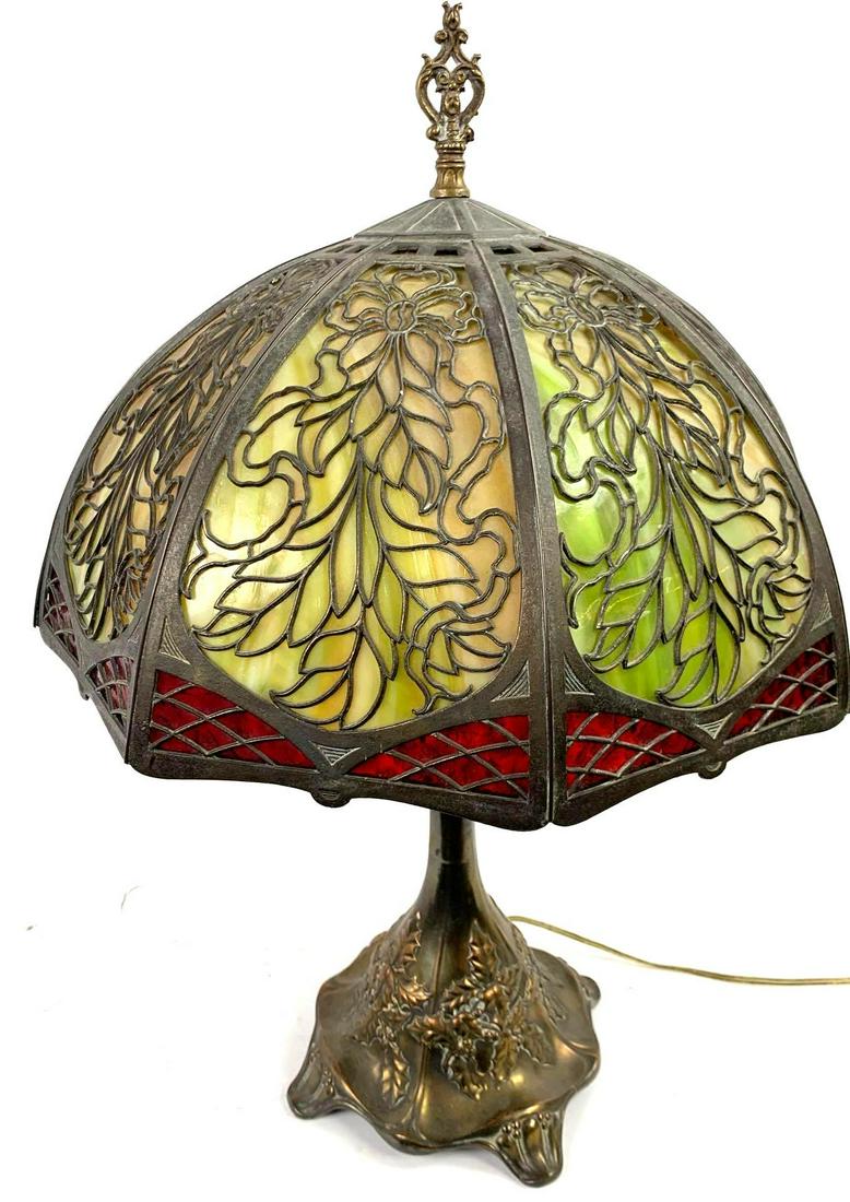 Slag Glass Table Lamp: Slag Glass Table Lamp Brass lamp stand with holly leaves and berries. Slag glass shade with panels of marbled green glass and ruby red glass around the rim. Shade is attached with a brass finial. Appr