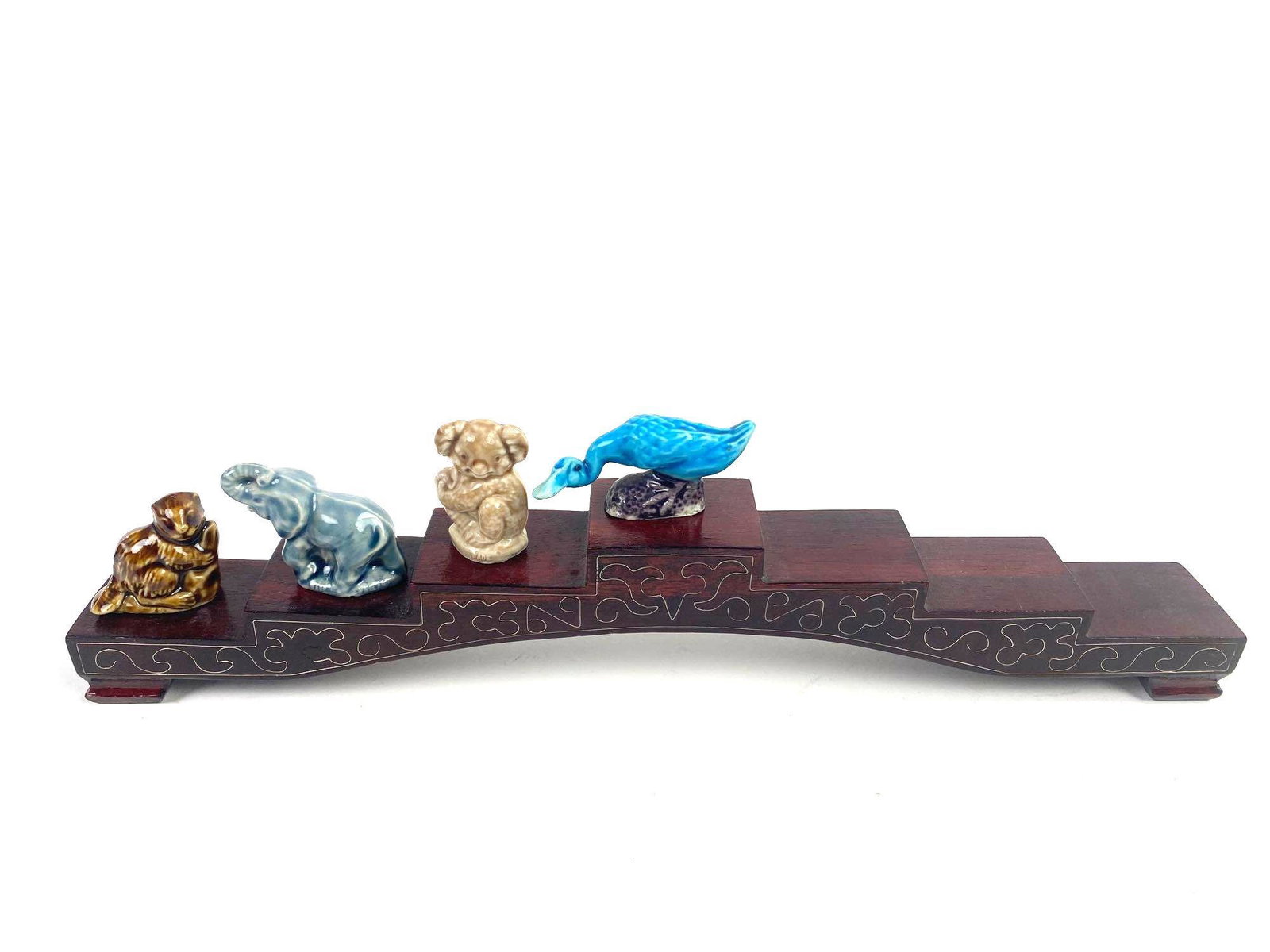Four Rose Tea Figurines with Stand: Set of four Rose tea figurines with stepped stand. Stand size: 1.5in wide x 12in long x 2in high Figurines include elephant, beaver, koala and goose.