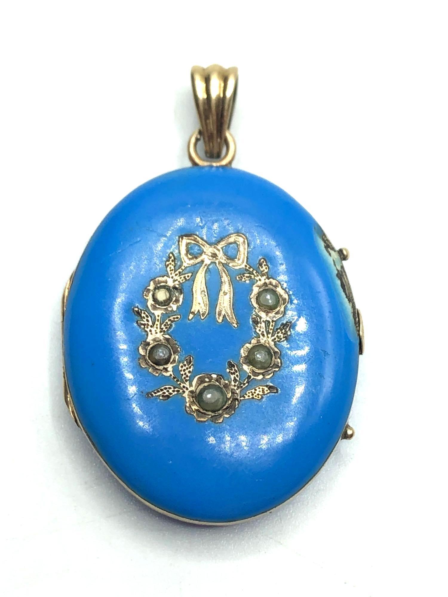 Victorian Mourning Locket: Blue enameled locket with bows and what appear to be pearls. Inside features a photograph of a woman on the right and hair along with a leaf on the left. Measures 1.5 inches long including bail and 1 