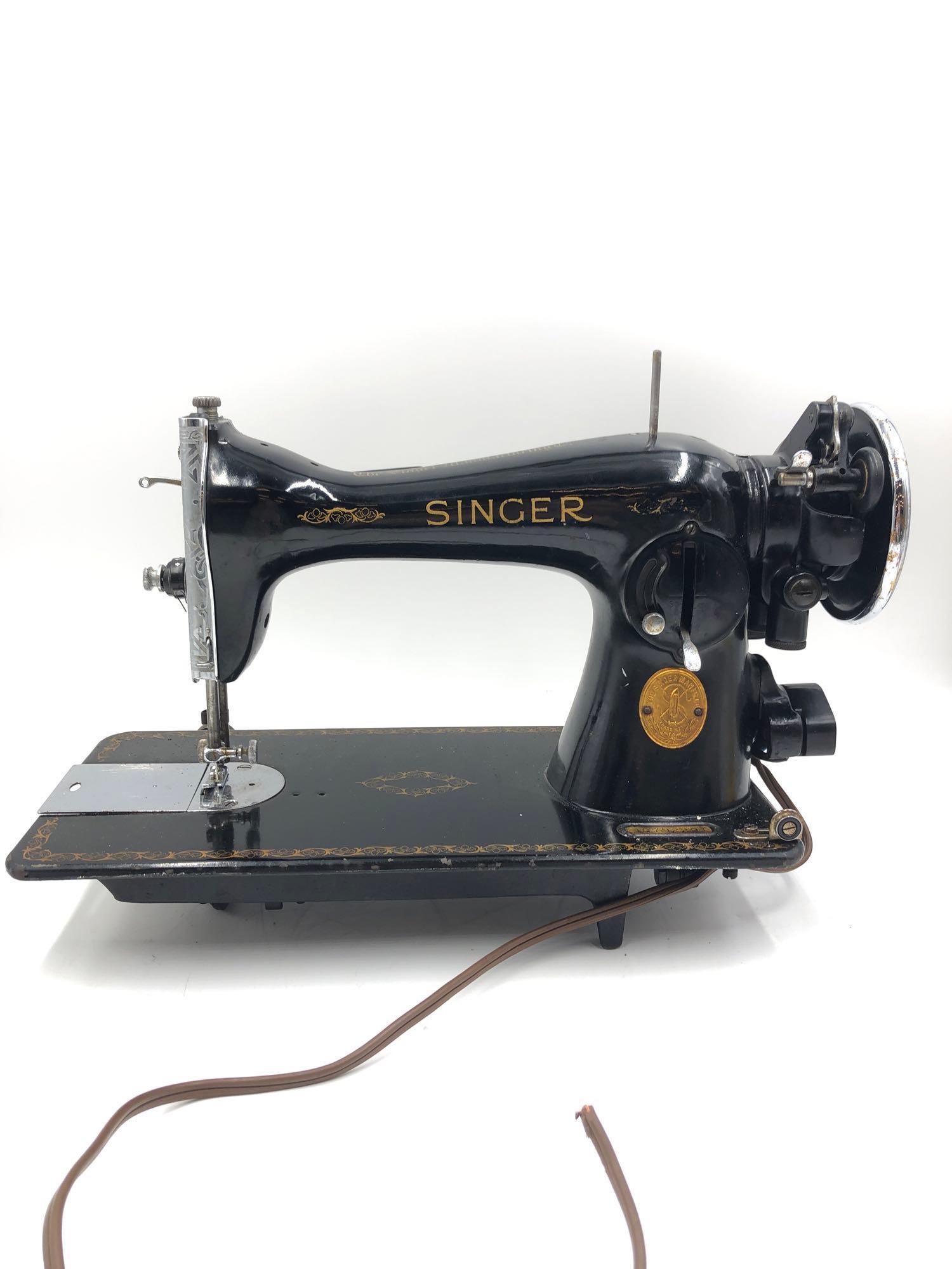 Vintage Singer Sewing Machine: Vintage singer sewing machine with ornate face plate above needle is serial number AG792291. Machine is missing the end to its power cord and its foot pedal. Measures 14.5 inches long 7 inches wide an