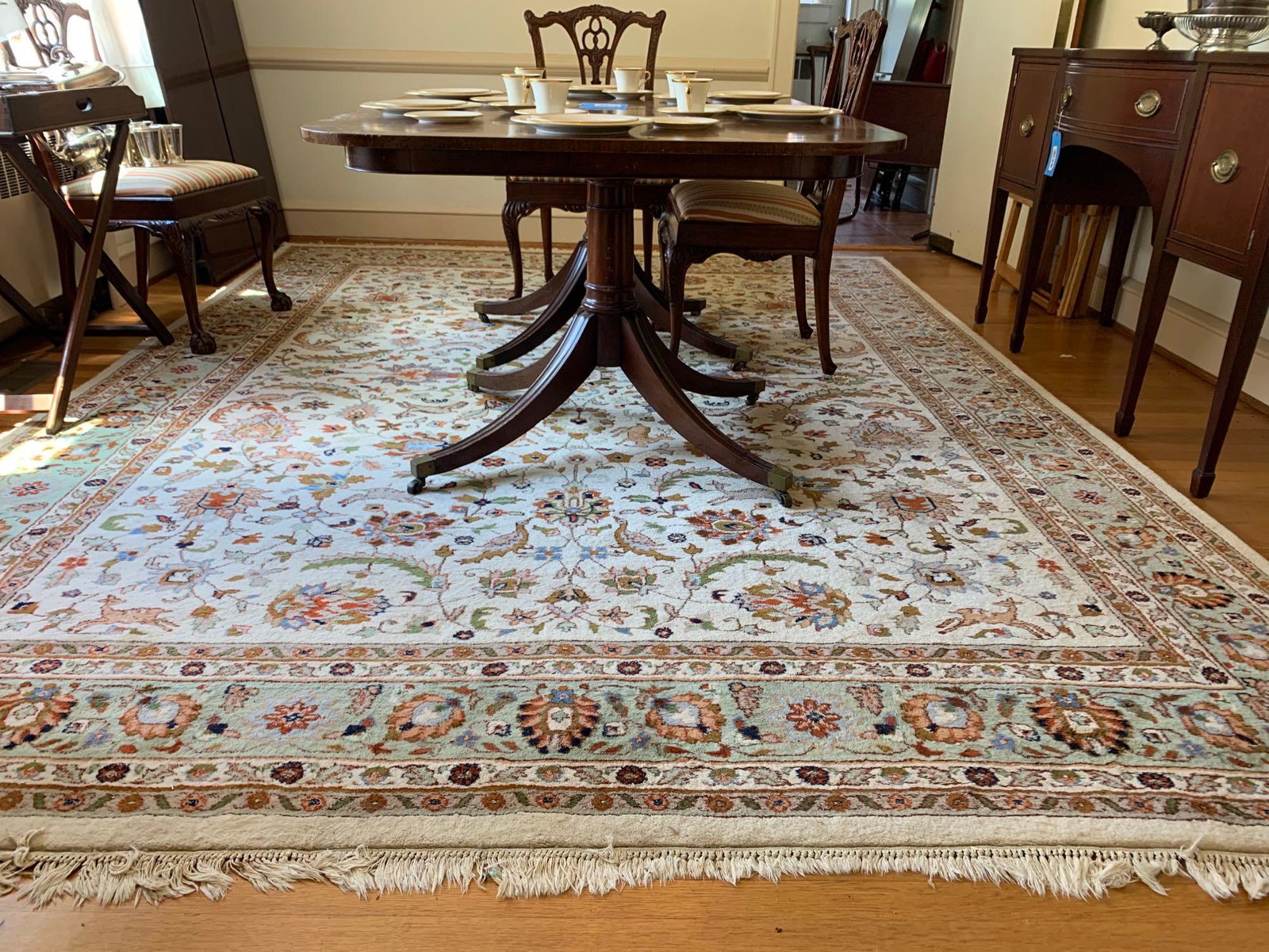 Large Area Rug: Large area rug with a fall scene of leaves, deer, and birds. It is in colors of cream, beige, brown, green, and red. The rug measures 147 inches long by 107 inches wide. ** Notice: This lot is located