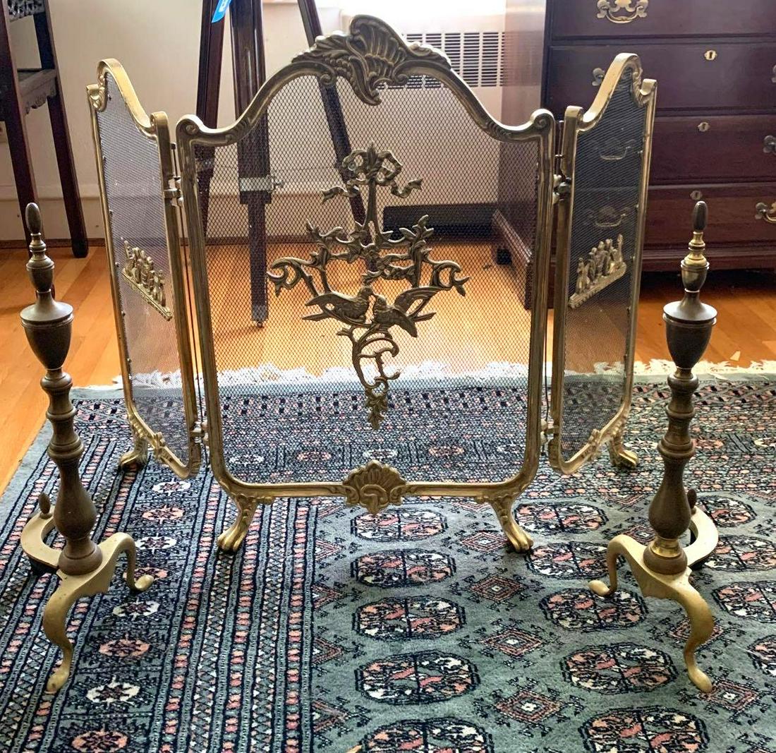 Brass Screen & Andirons: Brass fireplace screen with a lovebird design and a pair of brass andirons. The screen measures 41.25 inches long and 29.5 inches tall. The andirons are 22.5 inches tall. ** Notice: This lot is locate