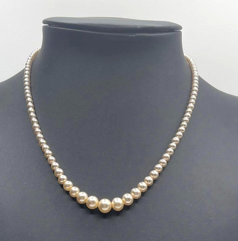 Pearl Necklace: Champagne toned pearl necklace which is closed by a fishhook clasp. Necklace is accompanied by a small piece of ephemera, a birthday note. Necklace measures 18 inches long.