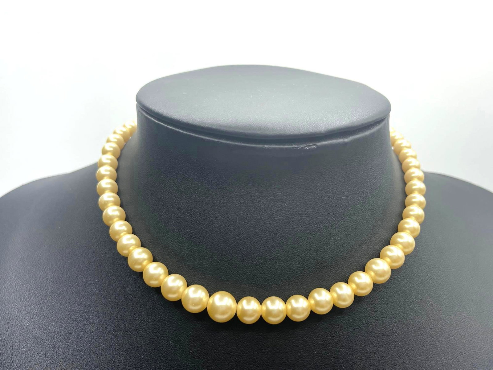 Marvella Pearl Choker: Marvella pearl necklace, featuring a set of dark gold colored pearls strung together. Necklace clasp is a silver toned metal, made into the shape of a ribbon bow. Marvella marking can be found on clas
