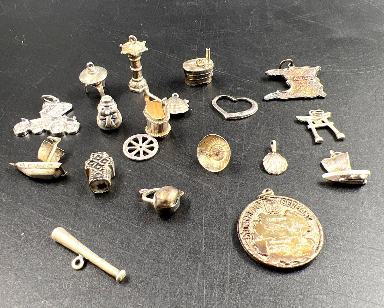 Collection of Sterling Silver Charms: In this lot is a collection of sterling silver charms. There are a total of 19 charms with a variety of themes and designs. Their collective weight is 1.03ozt and most measure less than 0.25 inches an