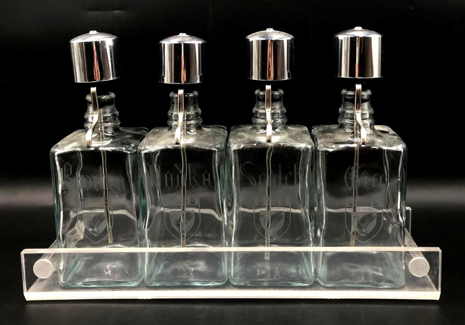 Duck Unlimited Four Glass Decanters on Tray: Ducks Unlimited Four Glass Decanters on Tray for Bourbon Vodka Scotch and Gin. Each bottle is for a different alcohol, with its name engraved and the Ducks Unlimited logo on the front. Each bottle has