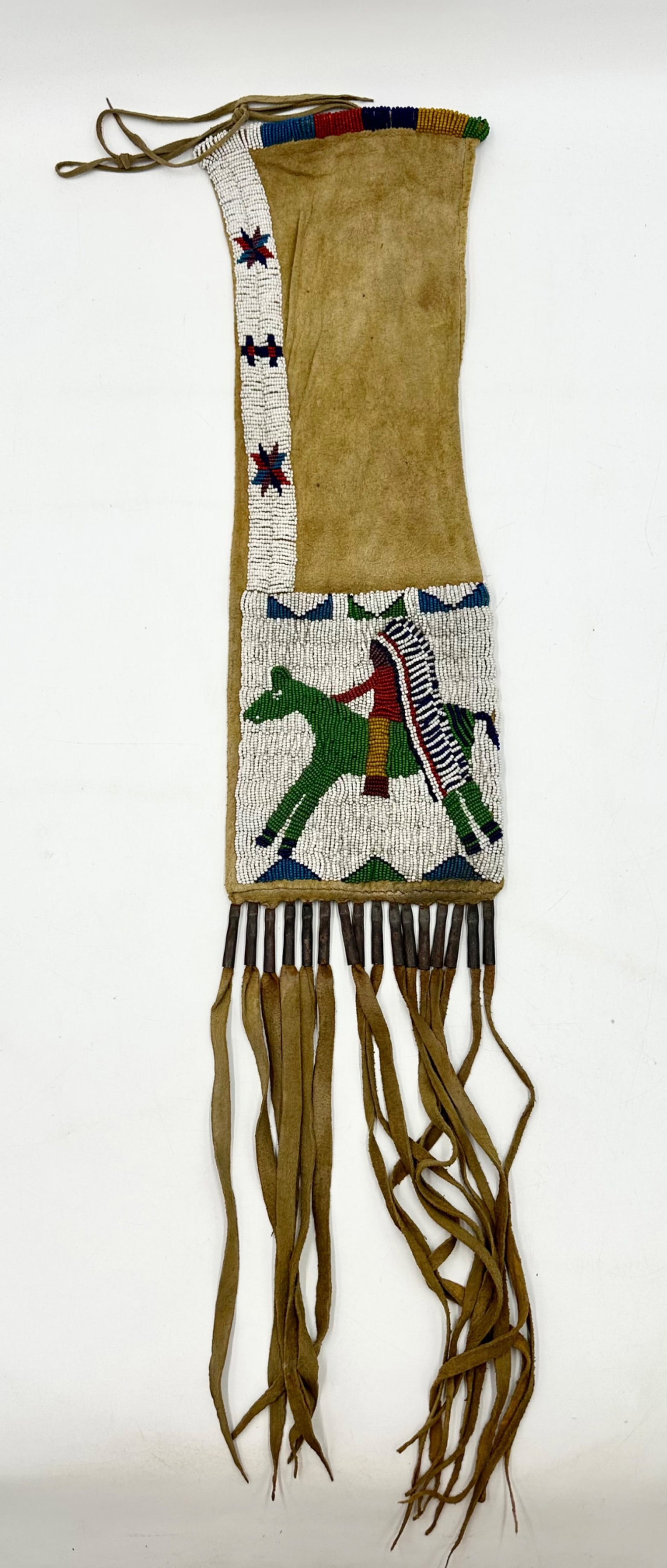 Pipe Bag: A Native American beaded pipe bag with a light tan hide and glass beads. The bead design creates a figure with a ceremonial head dress riding a horse along with star and cross shapes. The hide is frin