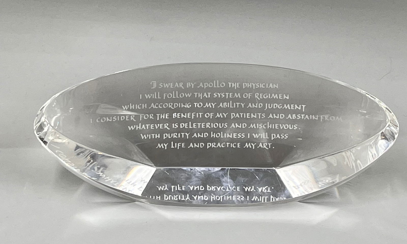 Steuben Glass Hippocratic Oath: A Steuben glass work of art with the Hippocratic Oath written on an oval-cut clear crystal plaque that stands on different edges. The piece was designed by George Thompson and Patricia Weisberg in 200