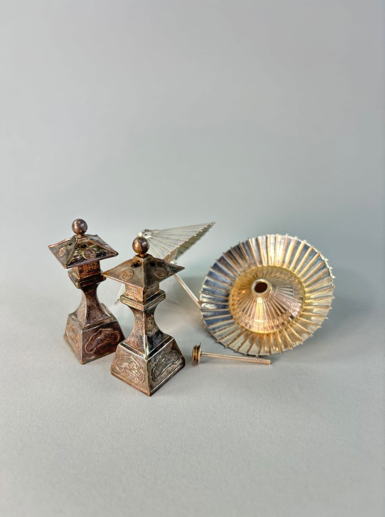 Sterling Silver Japanese Salt and Pepper Shakers: The sets in this assortment include a pair of sterling silver standing stone lanterns. The shakers are stylized with the curling roof design; embossed Mon crests, and floral mid-section. The base feat