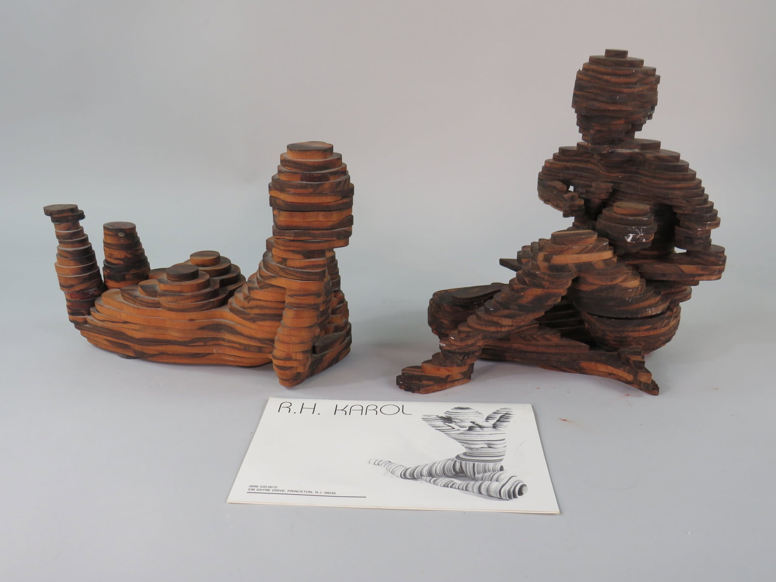 R H Karol Wooden Layered Statues: R.H. Karol wooden layered statues including a mother and child piece and a woman on her own. The mother and child piece features a darker stained wood and has the woman in a seated position holding he