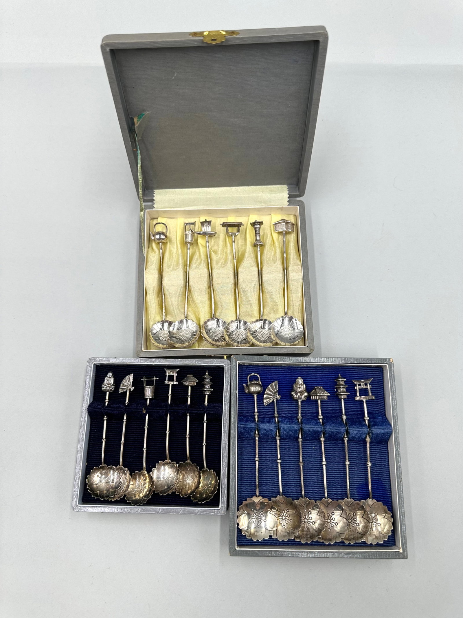 Three Sets of Sterling Silver Lotus Spoons: Three sets of sterling silver demitasse spoons each having six spoons in total. Each spoon is stamped "Sterling 950". The bowls of the spoons feature lotus flower designs and the handles are a bamboo 