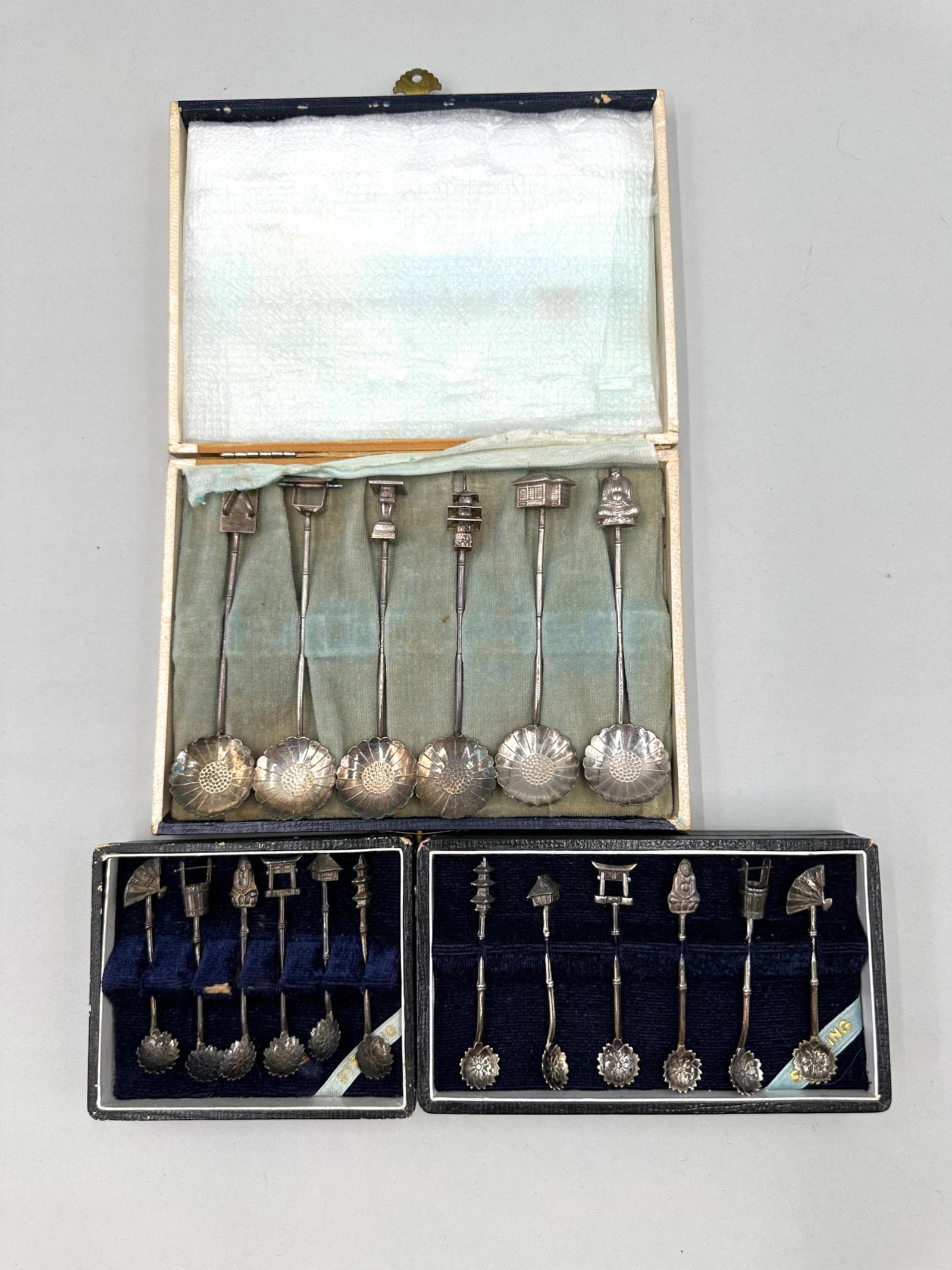 Three Sets of Sterling Silver Demitasse Spoons: Three sets of sterling silver demitasse spoons each having six spoons in total. Each spoon is stamped "Sterling 950". The bowls of the spoons feature lotus flower designs and the handles are a bamboo 
