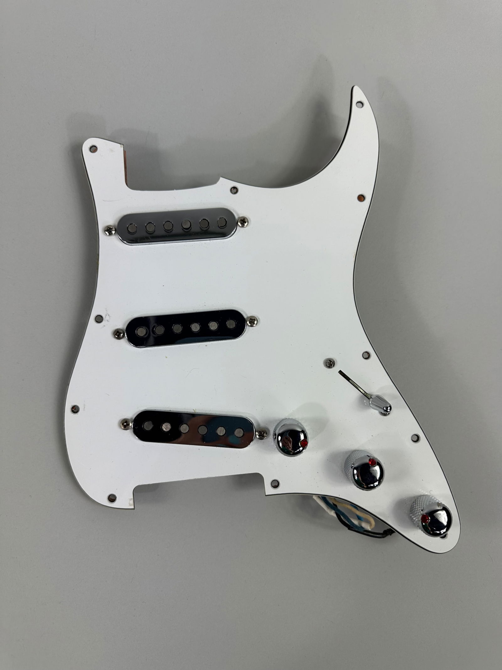 Prewired Stratocaster Assembly: Complete prewired Stratocaster Assembly including a Voodoo Tone Blender with silver pick ups and knobs with red rhinestones. Measures 9x11in An in-person inspection is available for all auctions. Blue