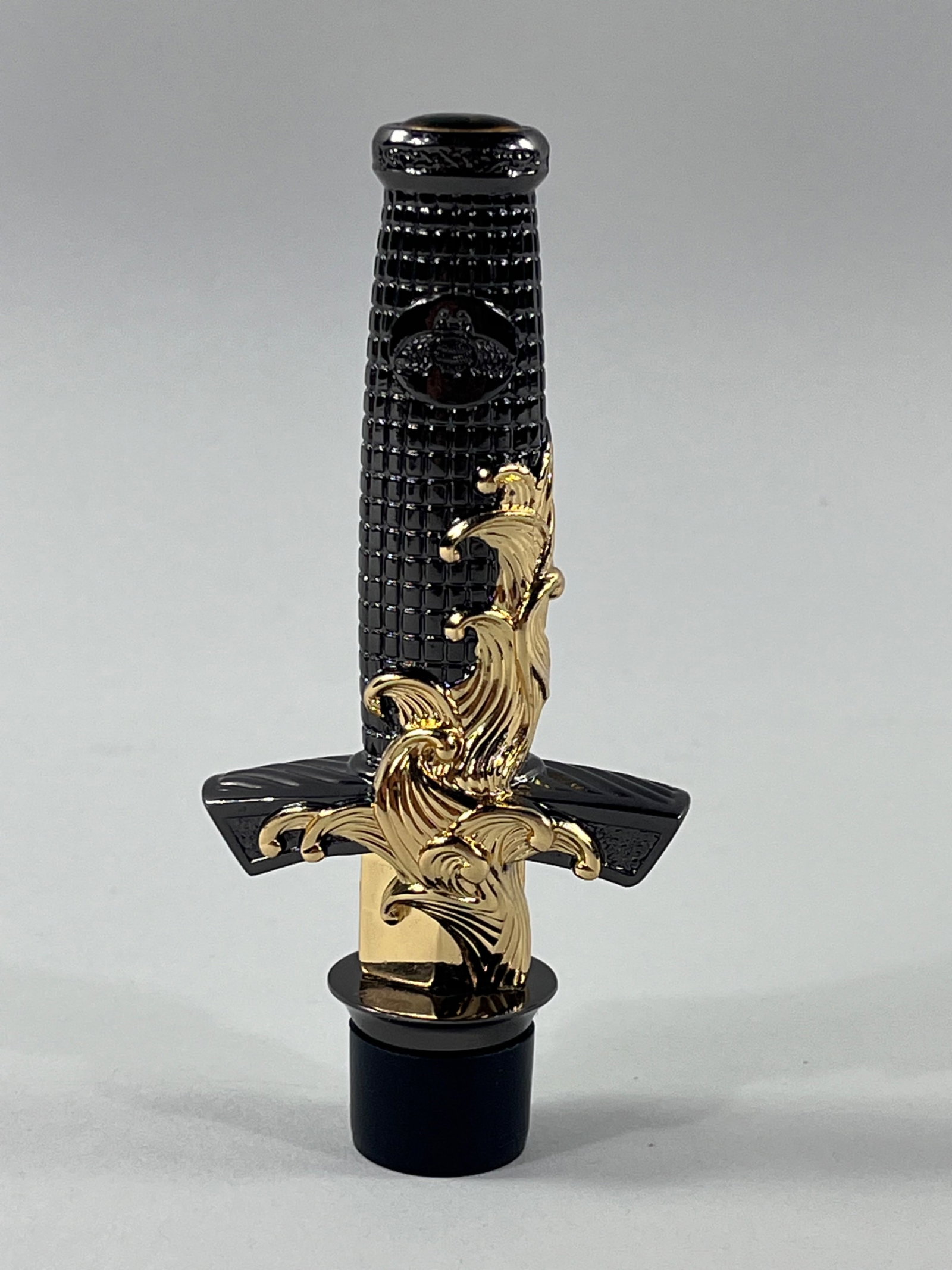 David Yurman Tequila Stopper: A highly decorative tequila stopper made by David Yurman in 2013. The stopper is rubber while the body is shaped like a sword handle. The body is two-toned with dark silver with a waffle texture and a