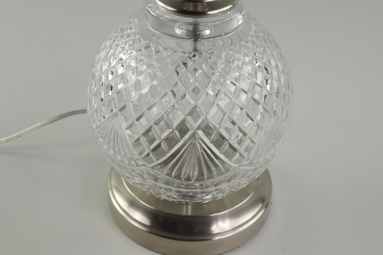 Waterford Crystal Lamp: A tabletop Waterford crystal lamp with a round ball design. The crystal is etched with a Gothic diamond-patterned top. There is a cut fan pattern around the center band. The lamp has a crystal top to
