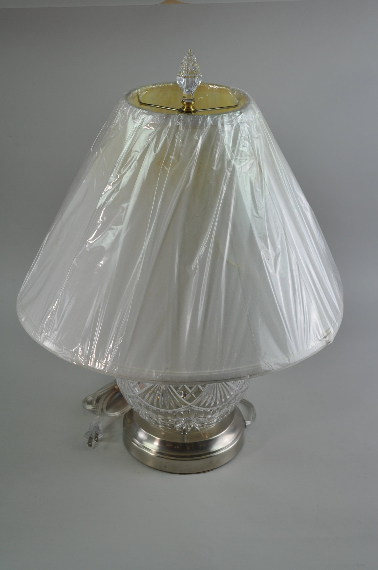 Waterford Crystal Lamp: A tabletop Waterford crystal lamp with a round ball design. The crystal is etched with a Gothic diamond-patterned top. There is a cut fan pattern around the center band. The lamp has a crystal top to