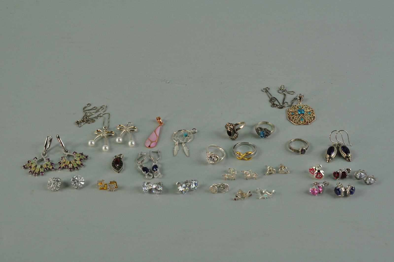 925 Sterling Silver Earrings, Necklaces and Rings: Three pairs of dangle earrings that are stamped 925. The earrings have latches or fish hookbacks. The earrings have different designs and are decorated with blue sapphires, purple amethysts, and tourm
