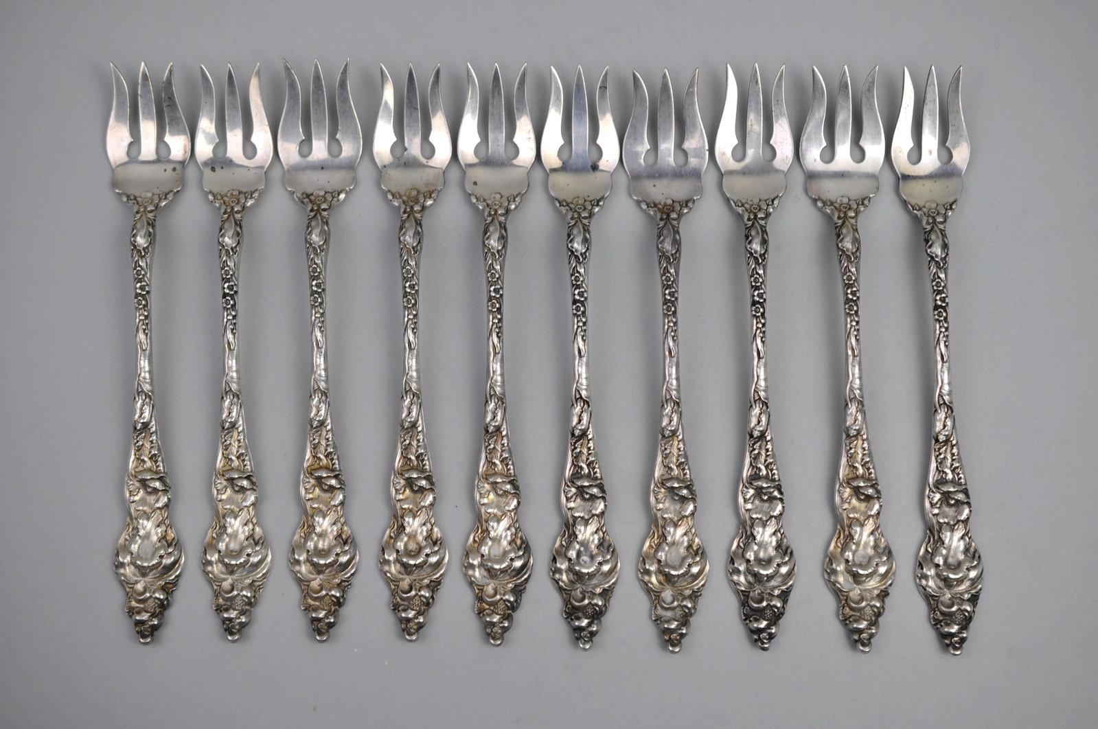 Reed Barton Les Six Fleurs Sterling Cocktail Forks 10 Pc: Metal: Sterling Silver Manufacturer:?Reed & Barton Dimensions:?Approx?6" Weight:? 7.61ozt Condition: Light to Moderate Patina