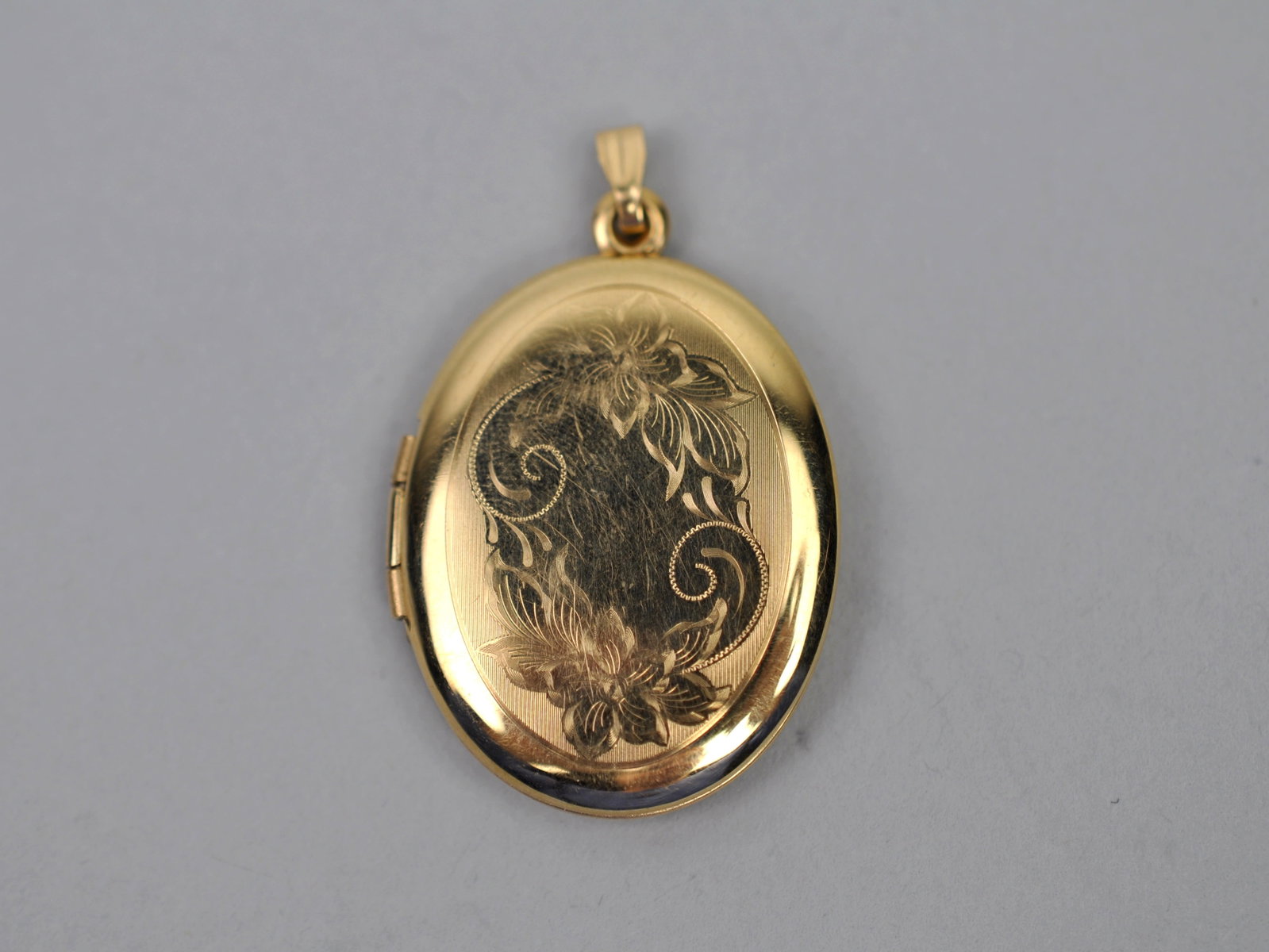 14K Gold Locket Oval Engraved: Metal:?14K Yellow Gold Stone Types:?None Dimensions:?Approx. 1/4" Weight:?Approx.0.15ozt Condition:?Light Scratches from Use Additional Information:?Decorative oval locket with engraved floral motif.