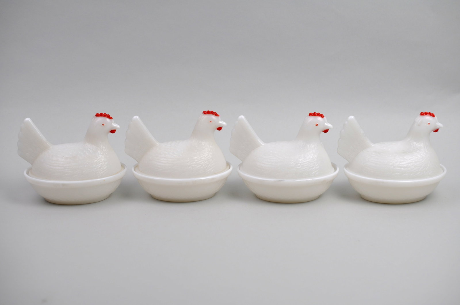 Milk Glass Hen on Nest Dishes: Manufacturer: Attributed to Indiana Glass Co. Dimensions: 3 1/2x4 1/2x4 1/2 in. Each Condition: No Visible Damage Additional Information: This set of four vintage milk glass hen-on-nest dishes is a