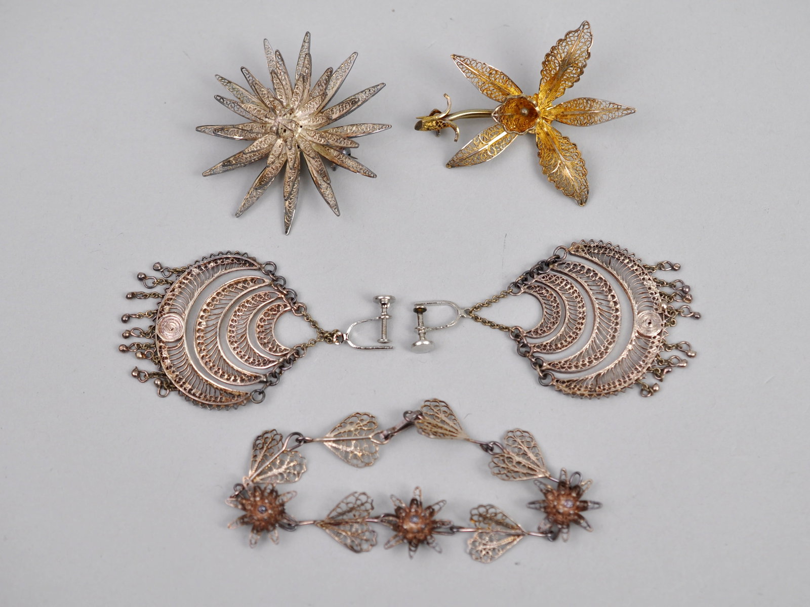 Filigree Metalwork Brooches Earrings Bracelet: Metal: Silver-Tone and Gold-Tone Metal Stone Types: Clear Rhinestones Dimensions: Brooches approximately 2.5-3 in.; earrings approximately 1.5-2 in.; bracelet approximately 7 in. Weight: Combined