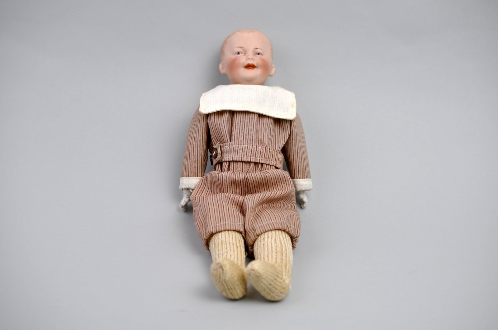 Gebruder Heubach German Doll: Manufacturer: Gebruder Heubach Dimensions: Approx. 11 1/4x3 in. Condition: Hairline Crack on Index Finger of Right Hand, No Shoes Additional Information: This charming Gebrüder Heubach German doll