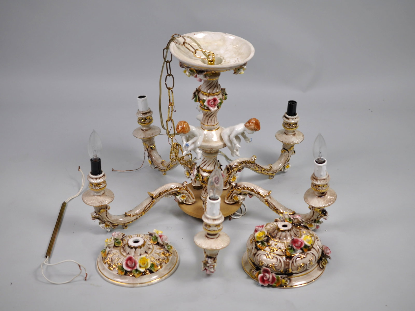 Capodimonte Chandelier w/ Porcelain Strap: Dimensions: Approx. 17 in. Tall & 30 in. Wide Condition: Untested and Disassembled. Has Repair Made Previously. May Contain Light Chipping or Cracking Due to Age Additional Information: A white and