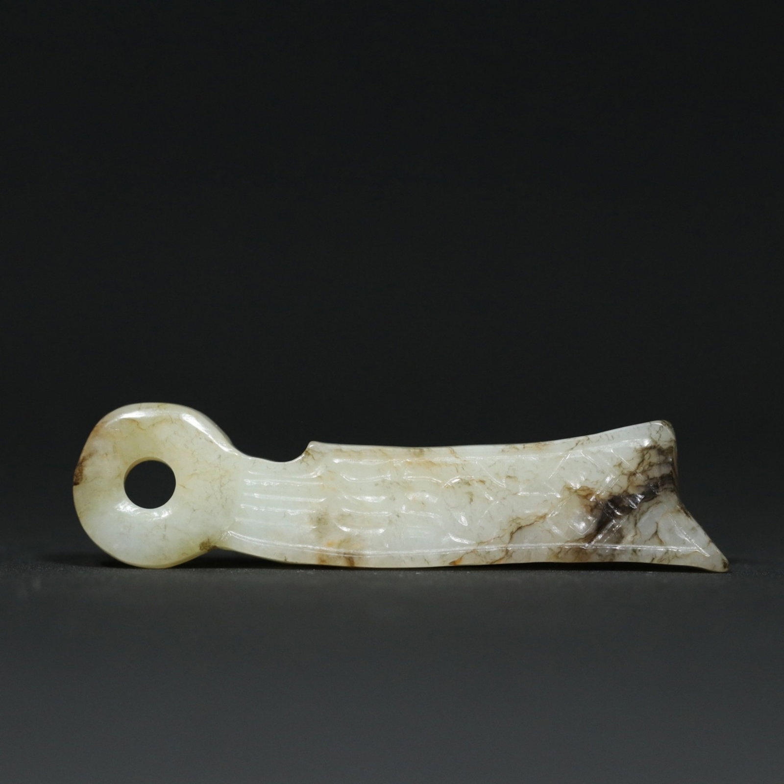 A Chinese Carved Jade Knife Pendant: Lg. 6.7cm, Wd. 1.6cm, Th. 0.6cm, Wt. 12.8g