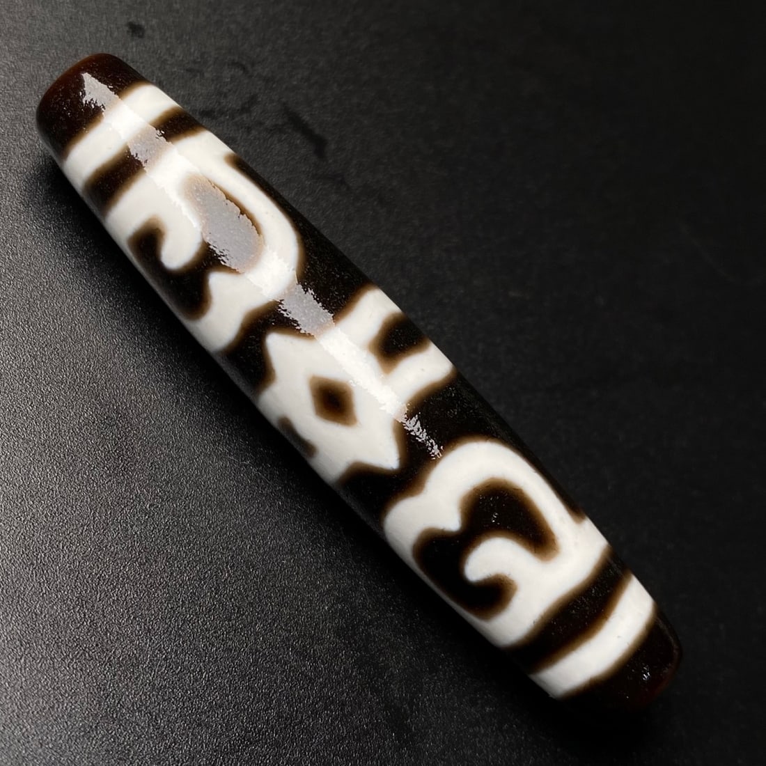 A Chinese Carved Agate DZI Bead: Ht. 5.8cm, Diam. 1.2cm, Wt. 13.2g