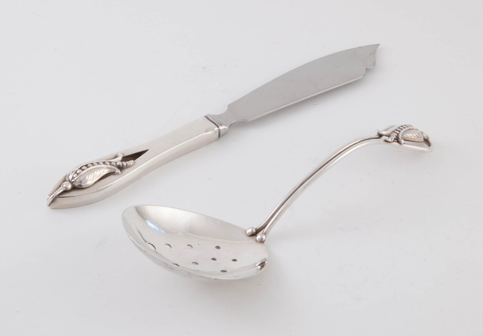 Carl Poul Petersen Blossom Corn Flower Server and Cake Knife: Pea server hand hammer strainer bowl and cake knife with stainless blade and sterling handle. 3.63 t.oz. Pea Server Spoon: 8 in L, 2.63 t.oz.Cake Knife: 9 ¼ in L, 1 t.oz.