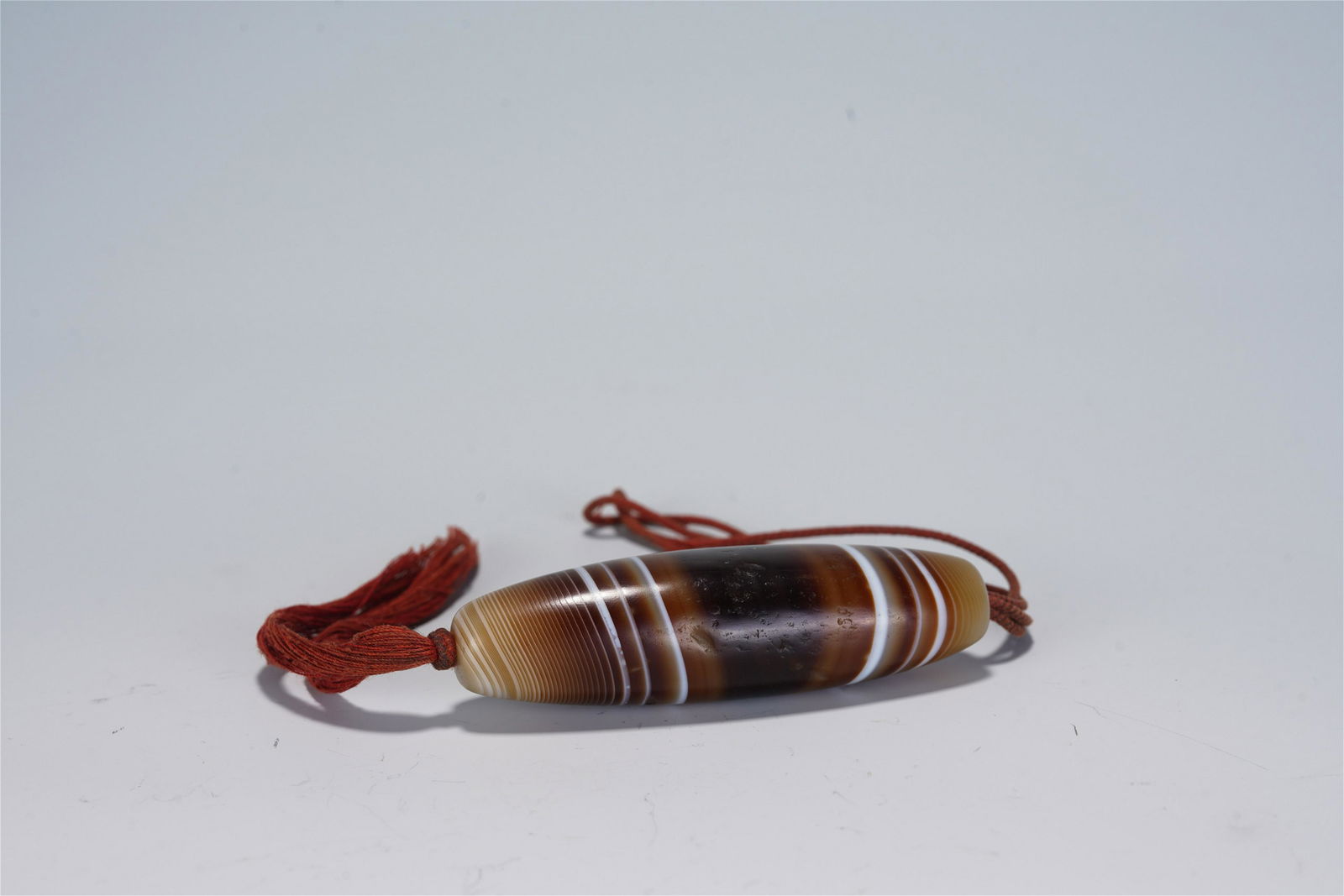 A CHINESE CARVED AGATE DZI BEAD (1 of 9)