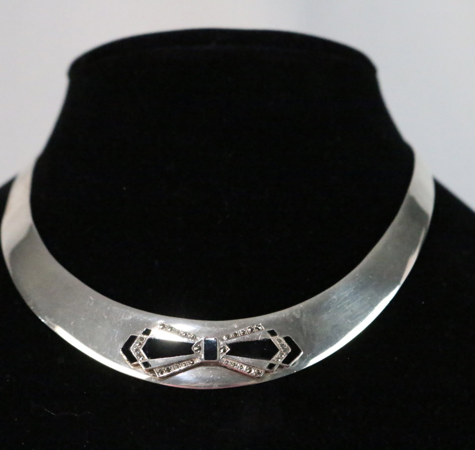 Sterling Silver Onyx Marcasite Bow Collar Necklace: Weighs 46.3 grams. Measures: .75mm at the back. Length is 13.5" with a 3" wide flexible opening. Width tapers center to back. Bow is 1. Stamped STERLING and has a makers mark with a 2 or a Z inside of