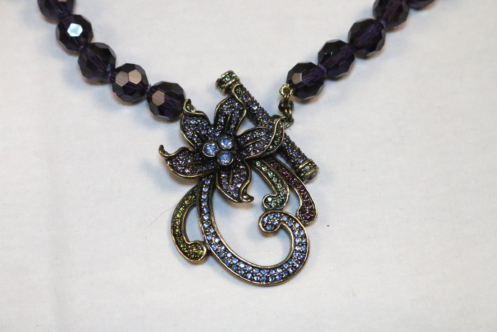 Heidi Daus Purple Faceted Lilly Crystal Large Toggle Necklace: Measures 32.5" including the 2.5 " purple, blue, green garnet crystals. EXCELLENT Condition. Stamped HEIDI DAUS.
