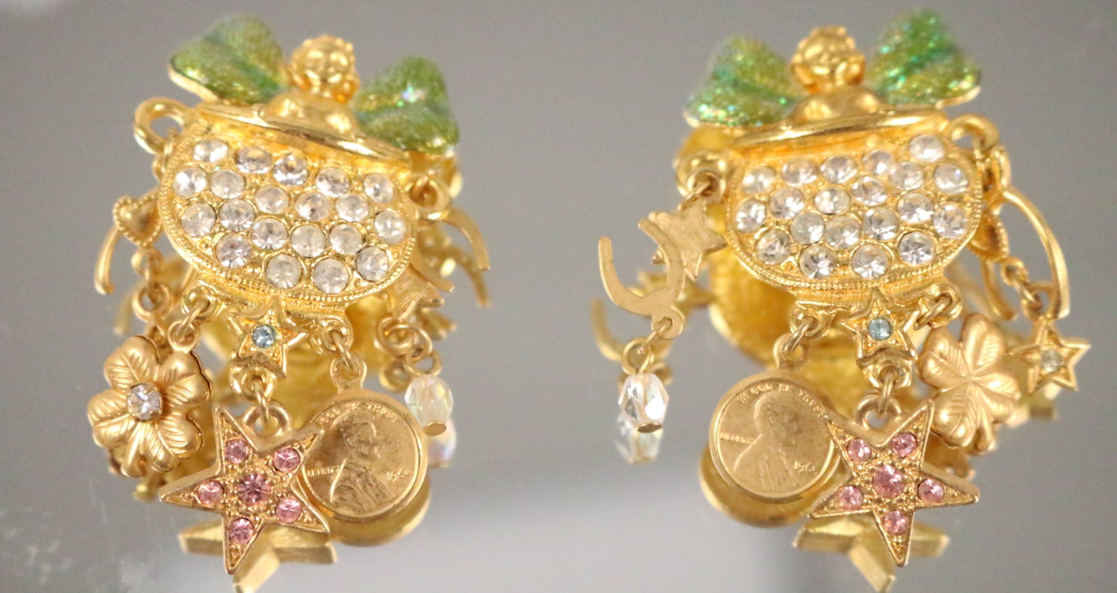Kirks Folly cherub Lucky Pot of Gold Coin Star Clip Earrings: Stamped: Kirks Folly. Enamel Glitter wings, stars, coins, 4 leaf clover, horse shoe and pot of "gold" Dangle Earrings. DIMENSIONS: 2" long x 1-1/4" wide.