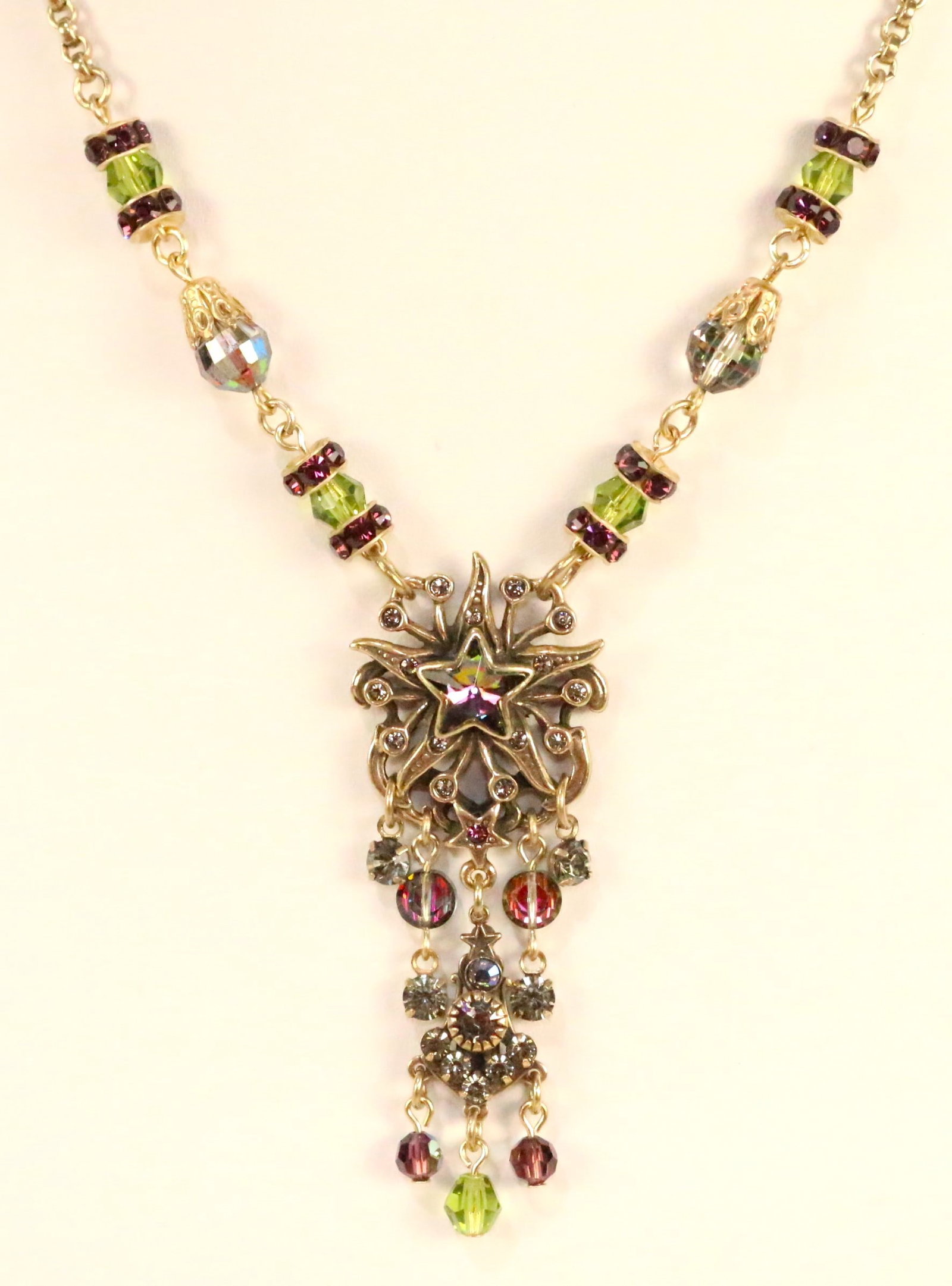 Kirks Folly Gold tone purple & green crystal Star Necklace: STAMPED: Kirks Folly DETAILS: Large Celestial star with a large purple crystal star center. Dangling purple and crystal beads. DIMENSION: 17" - 19" with the 2" chain extender. Pendant drop is 2.5". St
