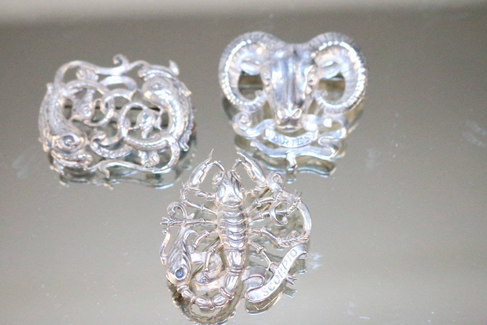 NEW OLD STOCK Sterling Silver CINI Zodiac Brooches lot of 3. ARIES, PISCES, SCORPIO.: SIGNED: STERLING BY CINI on the back. The fronts are marked each zodiac sign: Pisces, Scorpio, Aries. DETAILS: NEW OLD STOCK. Could use a polishing. Amazing large brooches. SIZE/DIMENSIONS: Each are a