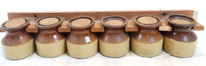 Wall rack holding two-toned, earthenware spice bottles and wood rack