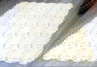 Off-white quilt with yellow/blue floral design and scalloped edges, 81" x 85"