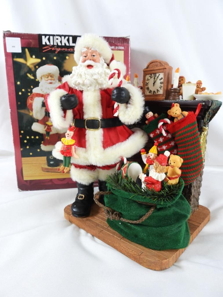 KIRKLAND SIGNATURE FABRIC MACHE SANTA in box: KIRKLAND SIGNATURE FABRIC MACHE SANTA, Item #212206, in original red box, with candy cane, sack of toys at fireplace with stockings and clock, candles and milk and cookies on mantle, 7"Lx7.5"Wx11"T