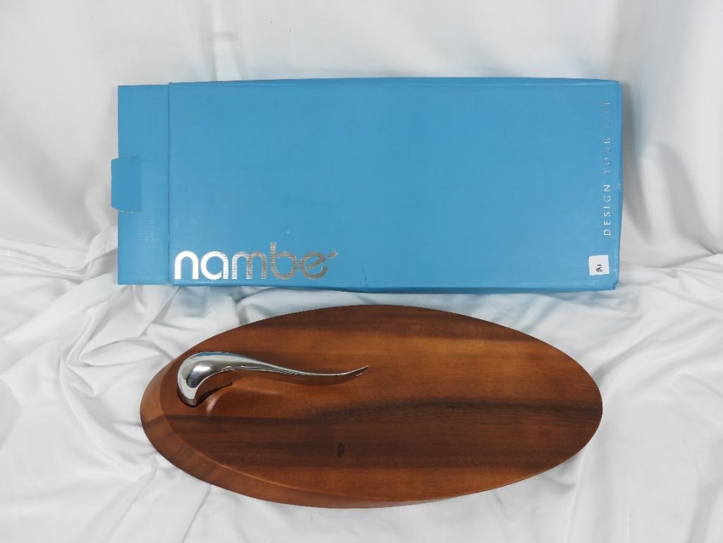 Nambe "Swoop Cheese Board" with knife: A solid wood cheese board made of acacia wood and features a contemporary style stainless steel knife