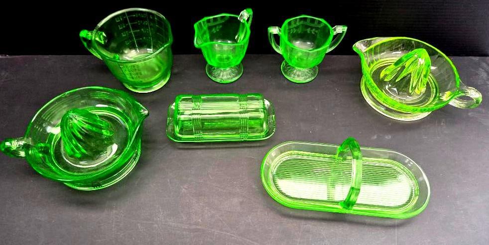 LOT OF 7 URANIUM DEPRESSION GLASS: Iconic uranium depression glass contains 2 juicing trays, a serving pitcher, double handled cup, measuring glass, a 9.5" serving tray, and a 6" butter dish