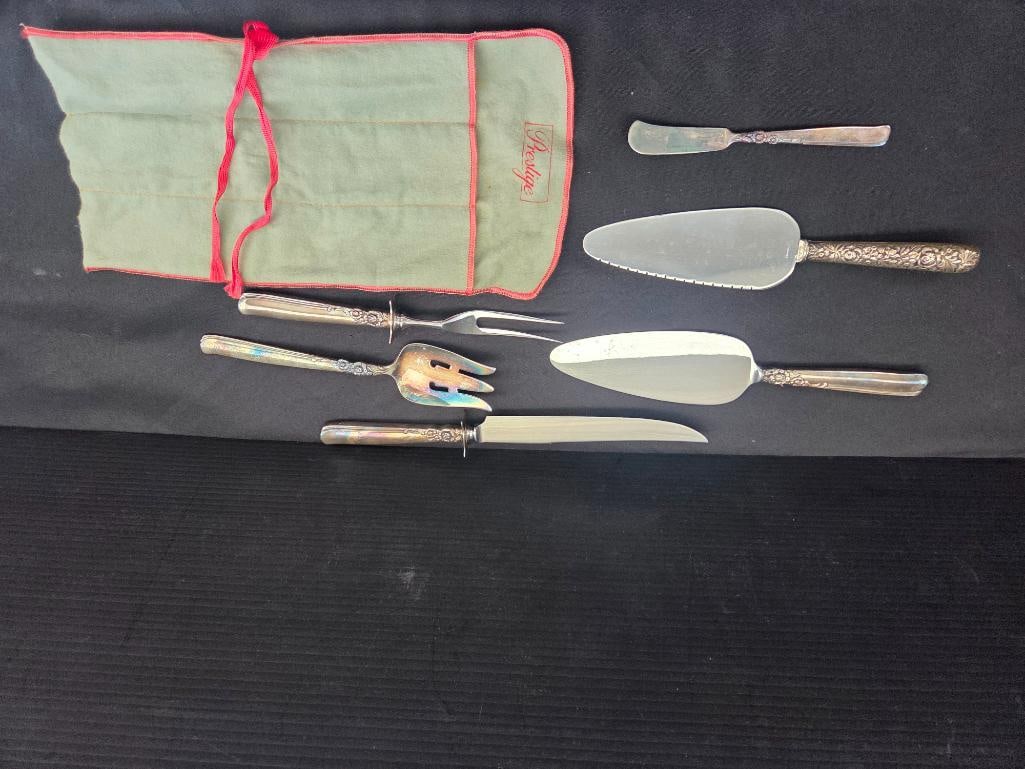 LOT OF 7 SILVER SERVING UTENSILS: Stainless steel heads are attached to silver plated handles including two flat serving spatulas, a serving for, two pronged fork, a large and smal serving knife complete with wool wrapping for storage