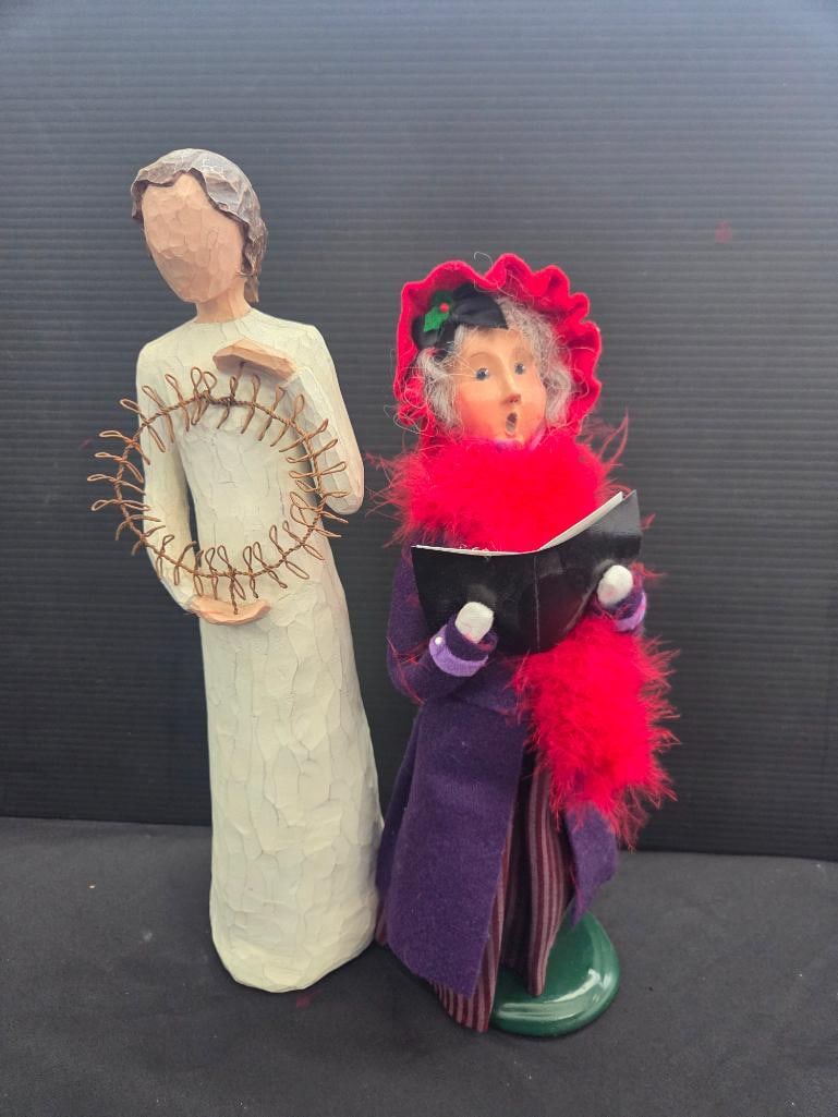 LOT OF 2 BYERS CHOICE/WILLOW TREE: Single caroler is dressed in purple wool with a red bonnet and red feathered scarf" tall and Byers signed, Willow Tree woman is named Welcoming spirit 15" tall and is holding a metal wreath