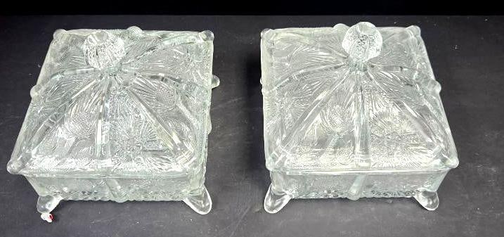 Pair of Pressed Glass Thistle Pattern Dresser Boxes: Matching pair of square lidded dresser/trinket boxes, pressed glass thistle pattern lids with starburst medallion center, short scroll feet. Approx. 4"W x 4"D x 3"H each.