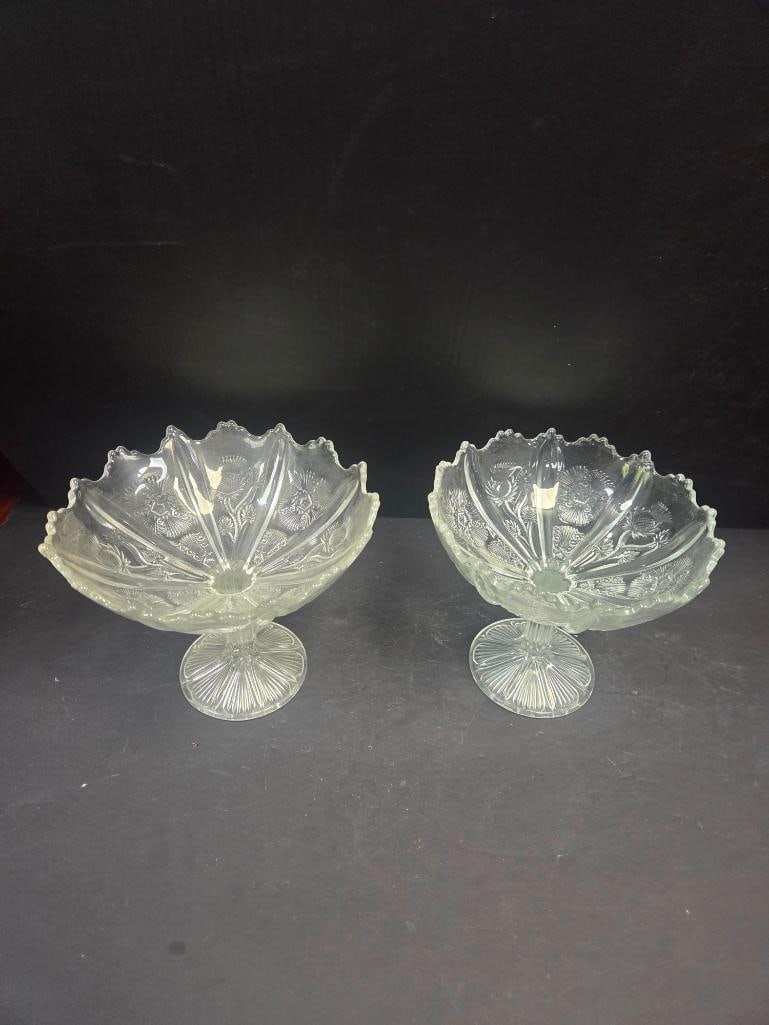 Pair of Pressed Glass Thistle Pattern Footed Compotes: Matching pair of footed compotes, fan-shaped bowl with scalloped/ruffled rim, thistle and floral pattern, on a round starburst-cut pedestal foot. Approx. 6"H x 7"W at rim each.